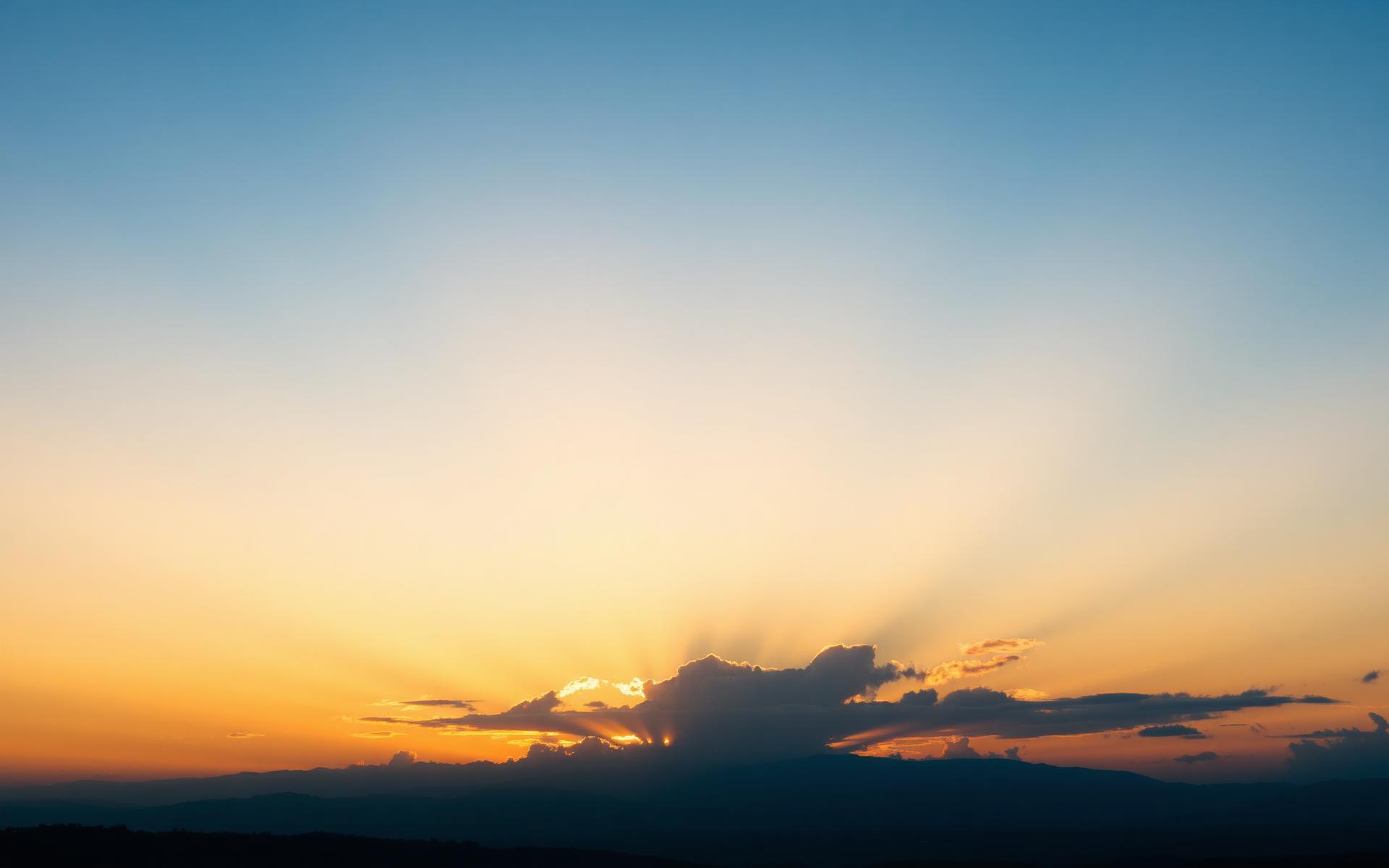 A predawn sky brightening toward sunrise, warm gold light emerging on the horizon